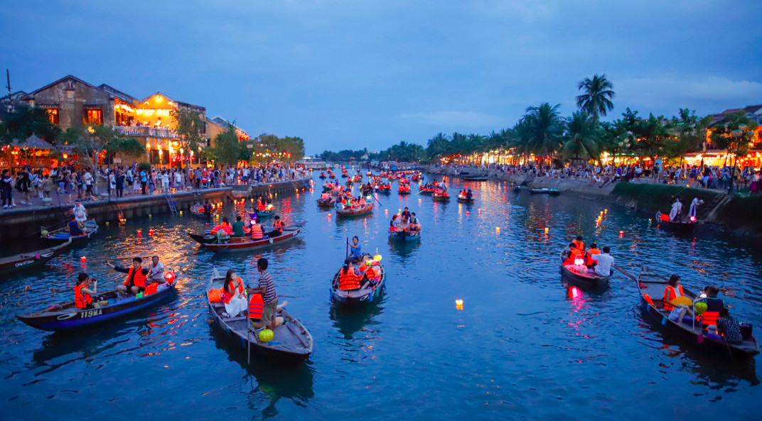 Khách du lịch thả hoa đăng trên sông Hoài Hội An bằng tàu gỗ